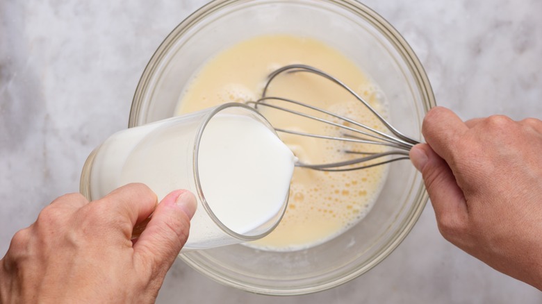 Hand whisking milk into batter