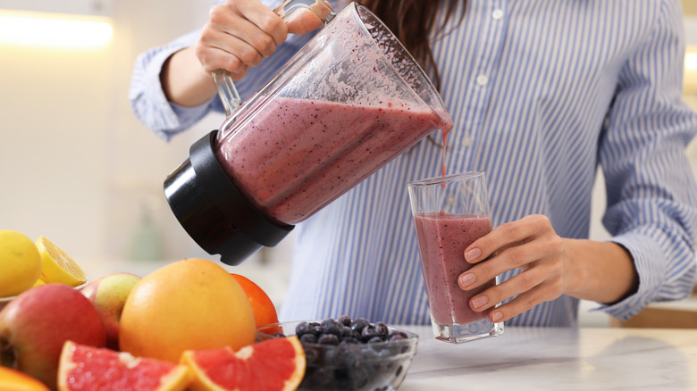 Person pouring smoothie out of a blender.