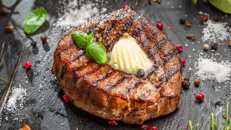 Grilled steak topped with a knob of butter and basil