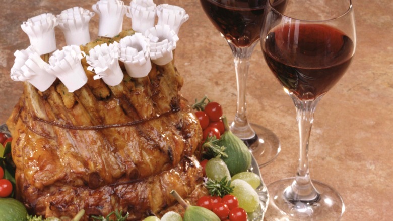 A crown roast with manchettes next to wine glasses