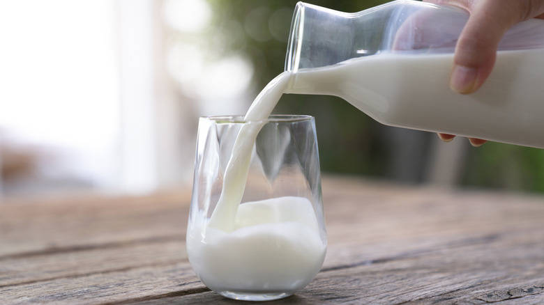 Someone pouring milk into a glass