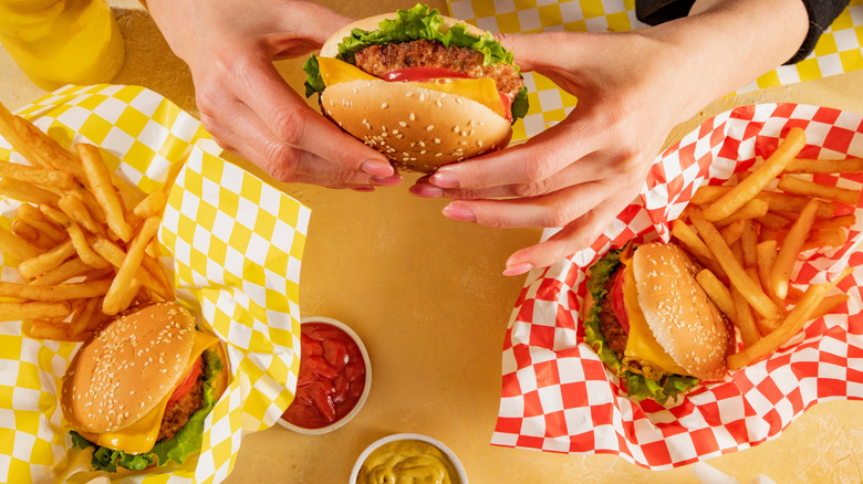 Top view of fast food cheeseburgers, fries, and condiments.