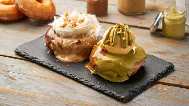 Gourmet chocolate and pistachio glazed donuts on a dark slate