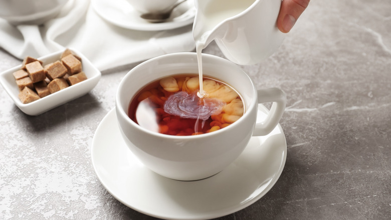 Pouring cream into a cup of tea