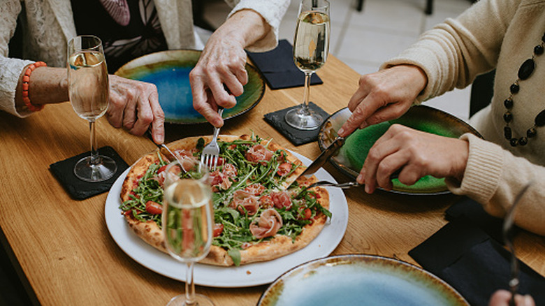 Diners eating pizza with Champagne