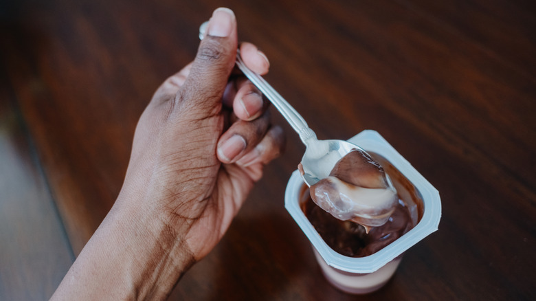 person scooping a bite of pudding from a disposable container