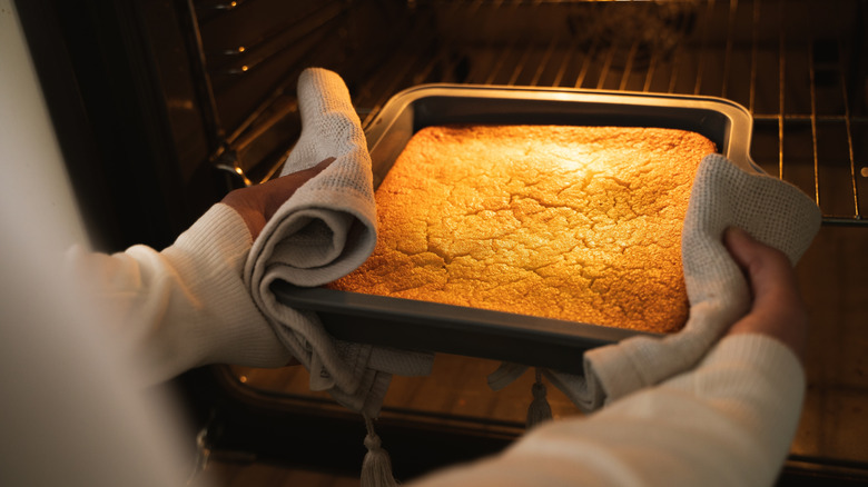 A homemade cake being removed from the oven