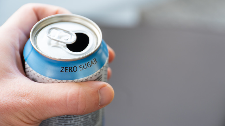Person holding a can labeled "zero sugar"
