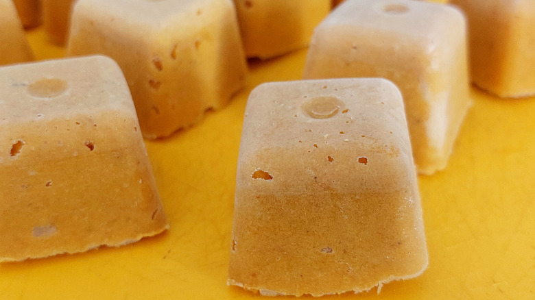Frozen broth cubes sit on an orange cutting board