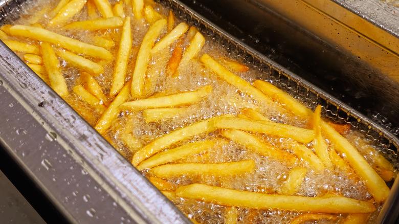 Golden brown french fries cooking in bubbling hot oil
