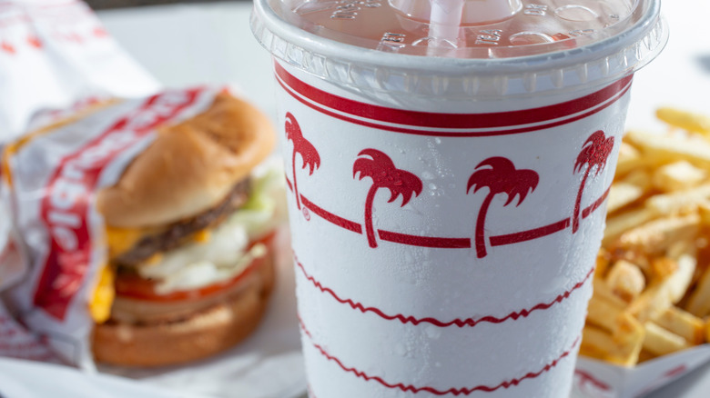 In-N-Out burger soft drink with palm tree logo on cup in front of burger and fries