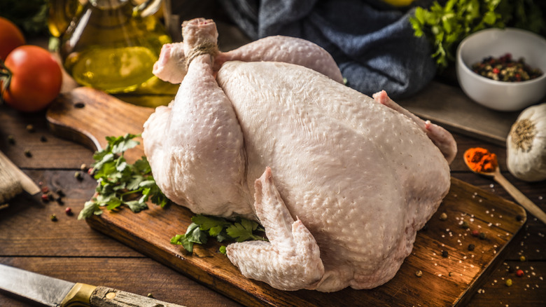 whole raw chicken on a cutting board 