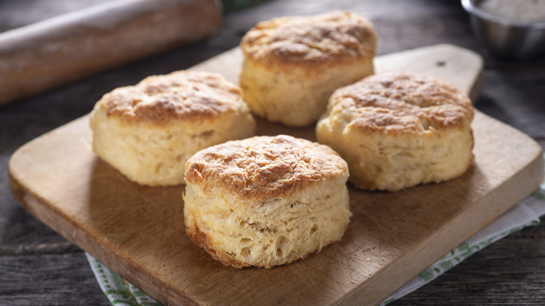 Four Southern buttermilk biscuits sit on a wooden cutting board