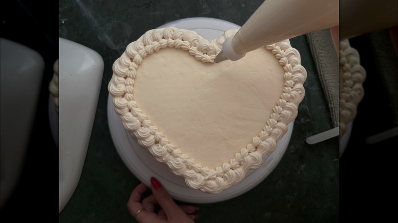 Baker decorating a heart cake