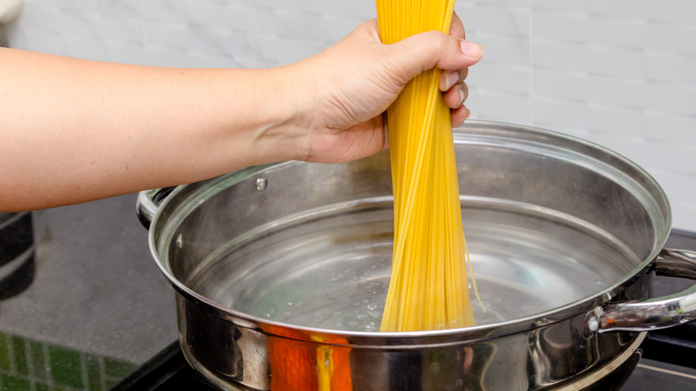 woman cooking angel hair pasta in boiling water
