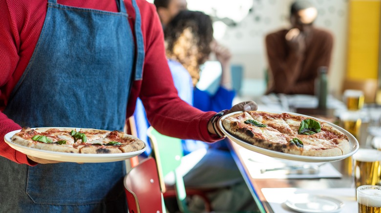 Waiter serving two pizzas