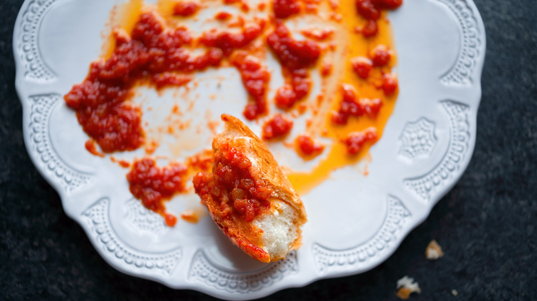 Bread scraping up sauce on plate