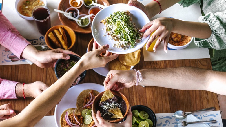 Group of people passing plates of food across the table