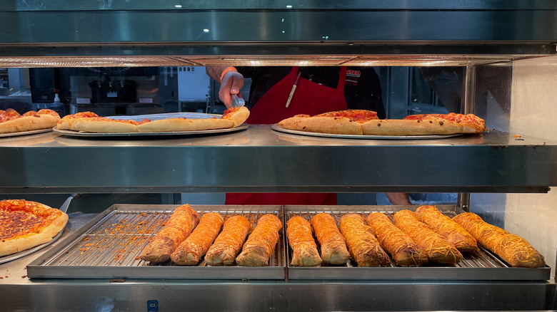 Costco food court pizza and chicken bakes under heat lamps