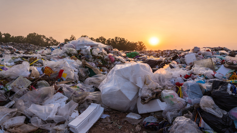 Close-up of large garbage pile with a sunset in the background