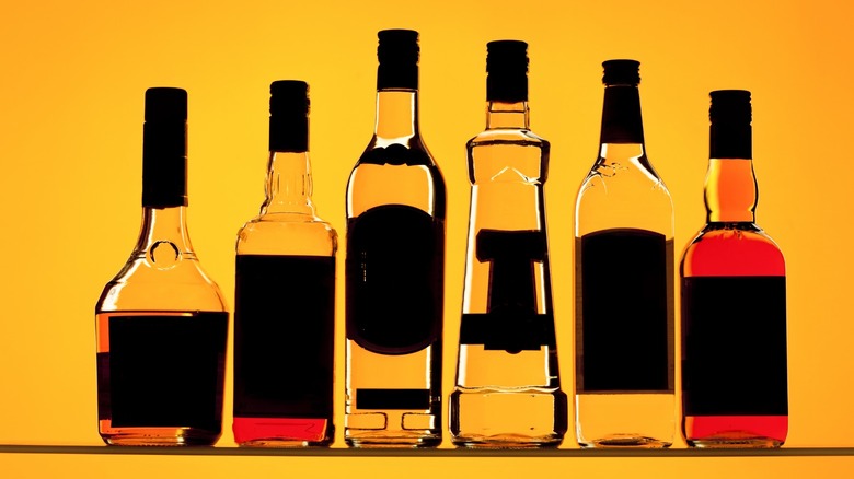 Various liquor bottles in a line on an orange background