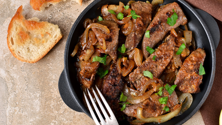 prepared plate of livers and onions with a side of toast.