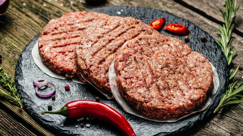 Raw burger patties on marble slab