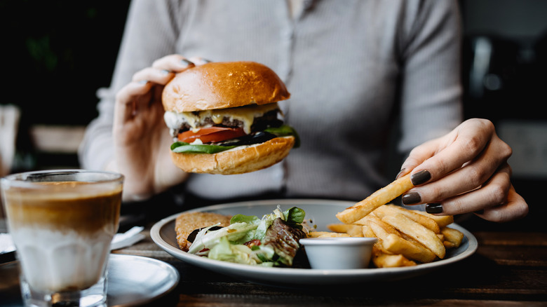 Diner eating a burger, fries, and salad