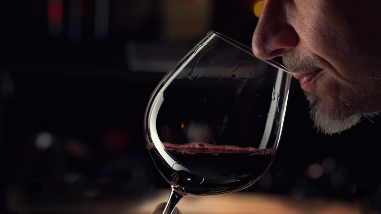 man nosing red wine glass