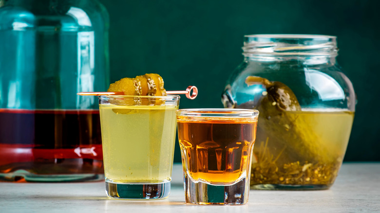 A shot of whiskey and a shot of pickle juice that is garnished with pickle chips