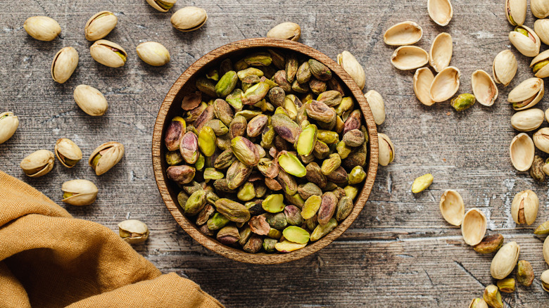 Pistachios in bowl surrounded by shells