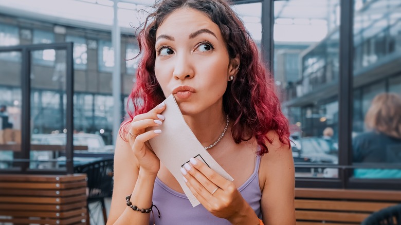 Woman wiping mouth with napkin in restaurant