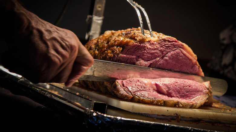 Someone carves into prime rib.