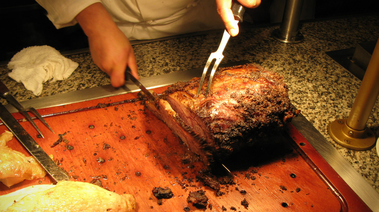 Chef carving prime rib at a buffet.