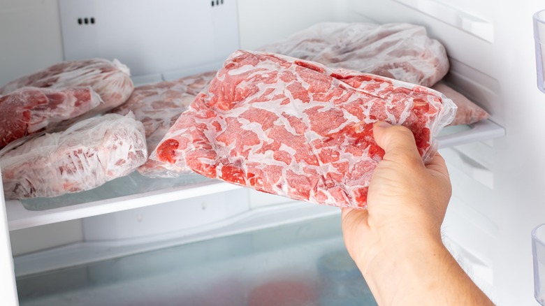 Person pulling frozen meat out of freezer