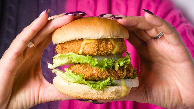 Hands holding fried fish sandwich
