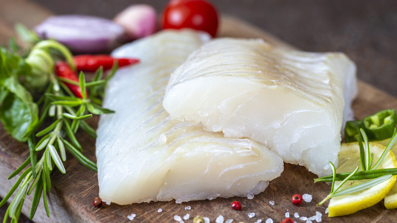 Raw white fish filets on cutting board with seasonings
