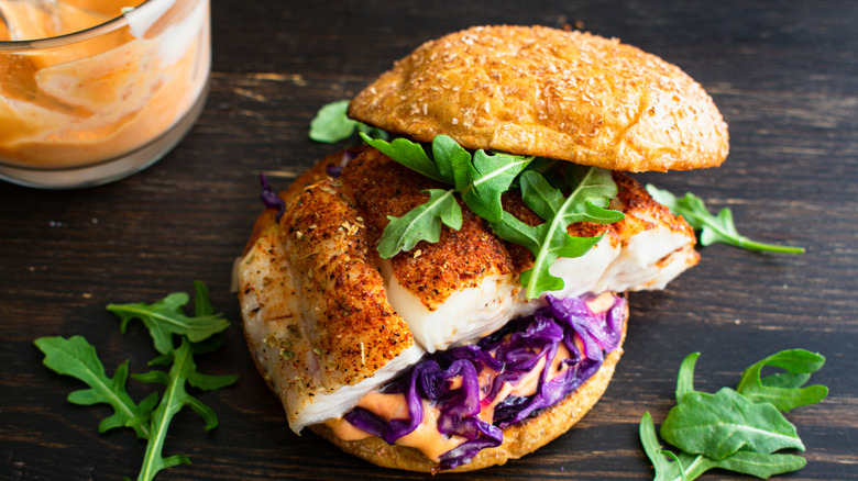 Blackened fish sandwich with arugula, purple cabbage, and remoulade
