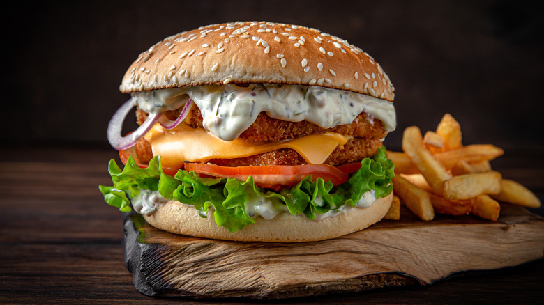Fried fish burger with lettuce, tomato, onion, cheese, and lots of tartar sauce