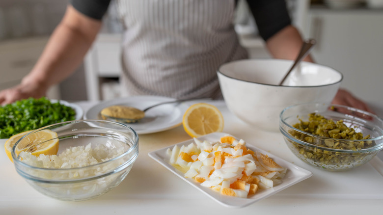 Cook standing in front of ingredients used to make tartar sauce