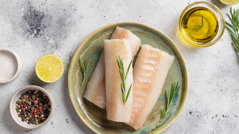 Raw fish filets with citrus, salt, oil, rosemary sprigs, and pepper