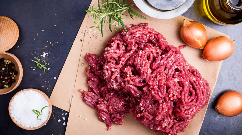A mound of raw ground beef alongside other ingredients