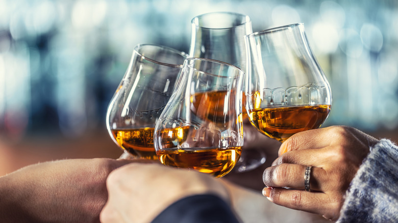 Four people toasting snifters of liquor