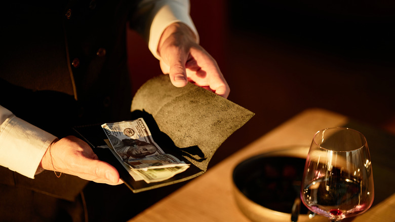 Waiter holding a bill with cash inside.