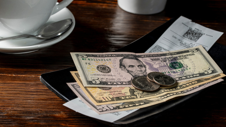 Cash left in tip tray at a restaurant.