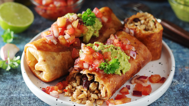Chimichangas served with a topping of salsa and guacamole.