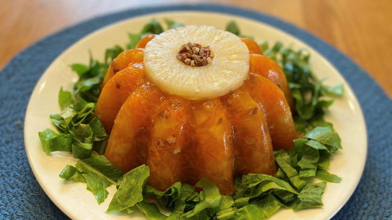 A molded gelatin salad featuring grated carrots and garnished with lettuce