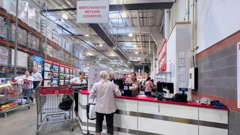 Customers stand at a merchandise return counter inside a Costco store