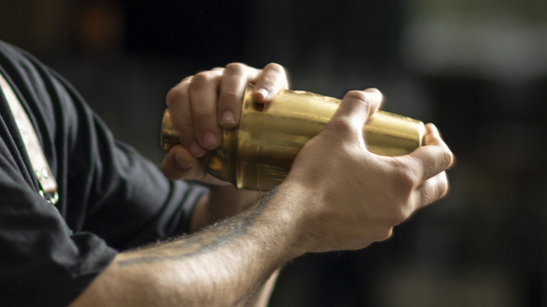 Bartender shaking gold cocktail shaker