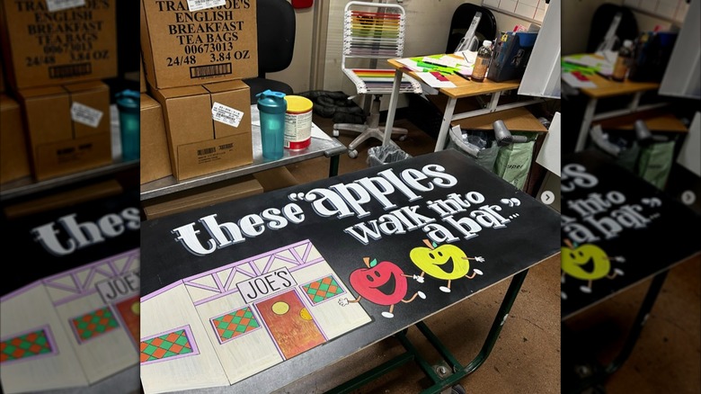 A Trader Joe's handmade sign about apples is shown in an employee work area of a store